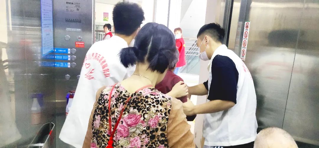 四川汽车职业学院支援着搀扶住院老人进电梯